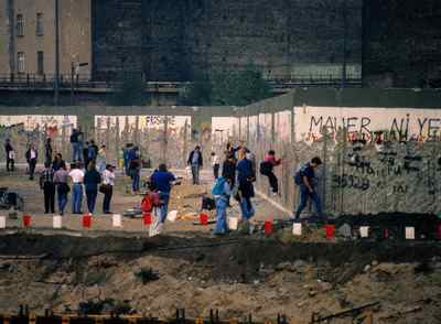 Souvenir hunters peck away at a part of the Berlin Wall after the city was reunited