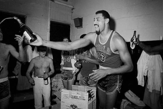 Wilt Chamberlain of the Philadelphia 76ers celebrates with champagne in the locker room after his team clinched the division in 1967.